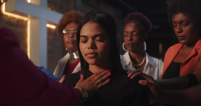 Praying in Christian church, diverse group of people laying hands on woman, spiritual support and blessing, faith-filled atmosphere, emotional and intimate moment