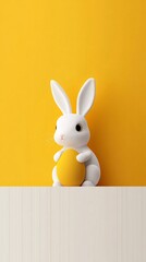 Obraz premium White easter bunny holding golden egg on yellow background