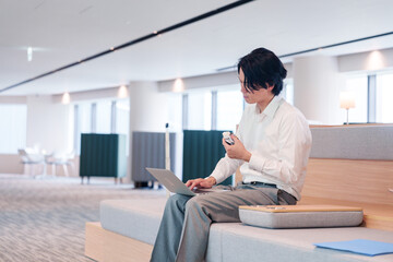 お昼ごはんを食べながらオフィスで仕事をする男性