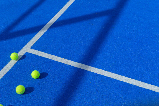 three balls in a padel tennis court blue artificial grass floor near the lines, racket sports background concept