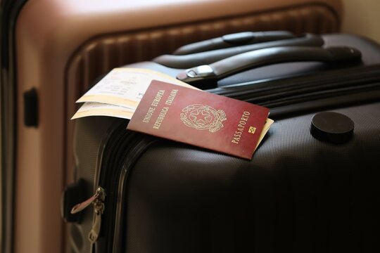 Italian passport with tickets lies on touristic suitcase close up in airport waiting hall