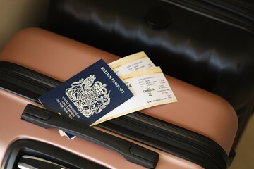 British passport with tickets lies on touristic suitcase close up in airport waiting hall