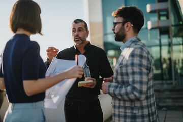 A group of multiracial business people engaging in a brainstorming session on a rooftop as the sun sets, fostering innovative ideas in an urban environment.