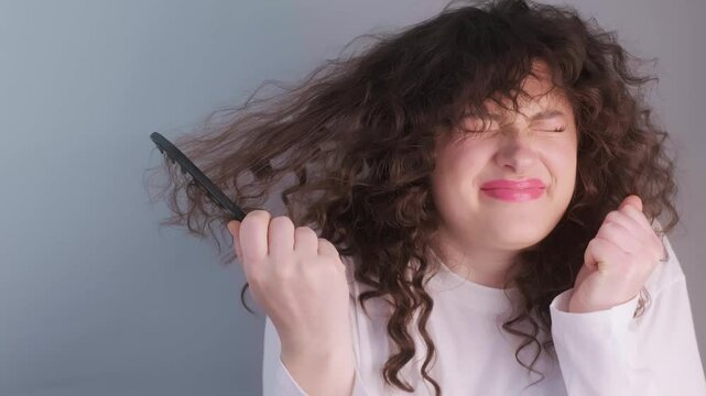 Morning curls are funny and painful at the same time as a woman struggles with knots and tries to tame her tangled curly hair