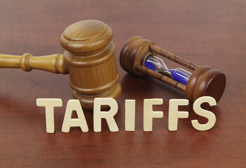 Words tariffs, hourglass and judge gavel on table. 