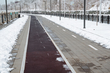 A snowy road features a bike lane situated right in the middle, allowing cyclists to navigate even...