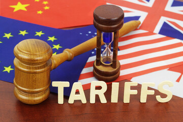 Judge gavel, hourglass, word tariffs and flags of USA, EU, UK, China and Canada close up. Tariffs...