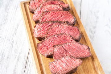 Perfectly sliced medium-rare fillet mignon steak served on cutting board