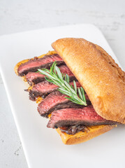 Grilled ciabatta sandwich with melted cheese, juicy steak, caramelized onions, and rosemary