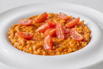 Creamy tomato risotto topped with cherry tomatoes on clean white plate