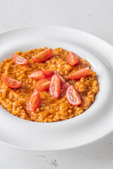 Creamy tomato risotto topped with cherry tomatoes on clean white plate