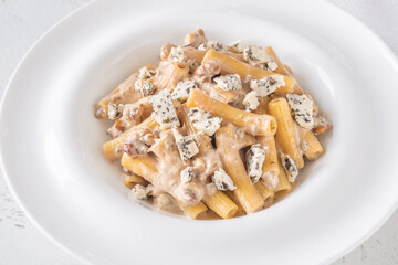Penne pasta served with creamy walnut blue cheese sauce on white plate