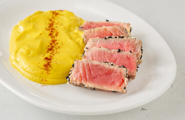Sesame-crusted sliced tuna with cauliflower curry puree on modern white plate