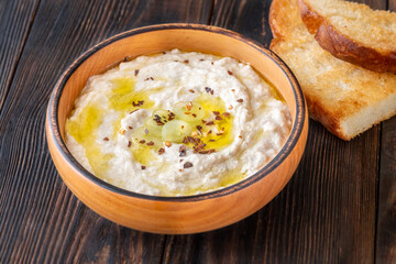 Creamy baba ghanoush in wooden bowl with chili and olive oil