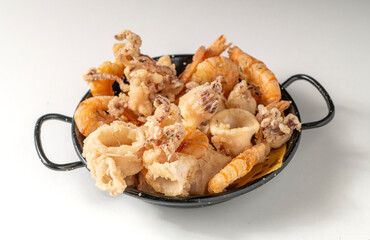 Fried fish with prawns and squid in a black basket, isolated on a white background. Minimalist style, golden tones, simple composition, traditional Italian dish.