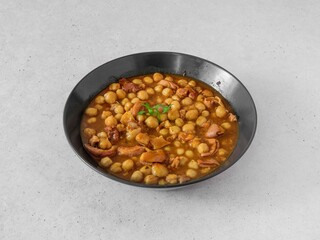 A bowl of food with meat and beans. There is a green leaf on top of the beans