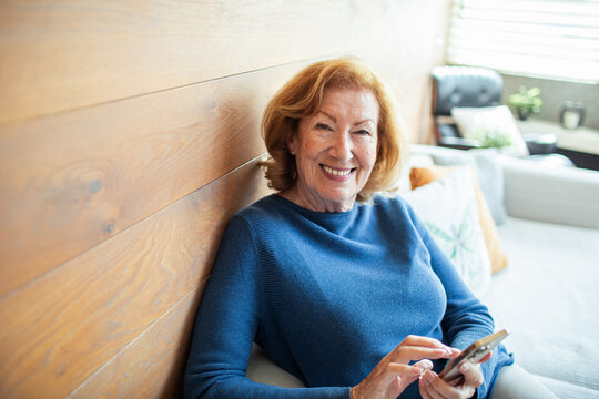 Senior woman using smartphone for video call or browsing at home