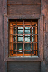 Small window with wooden grid in traditional rustic wall, softly lit by natural light. Ethnographic architecture, eco-lifestyle, heritage, rural craftsmanship