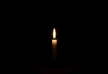 single candle is lit in the dark