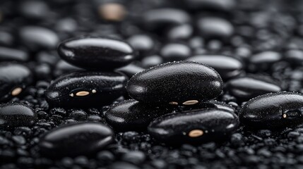 Close-up view of black beans.  A cluster of glistening, dark, black beans are densely packed together, showcasing their smooth surfaces and slightly oblong shapes