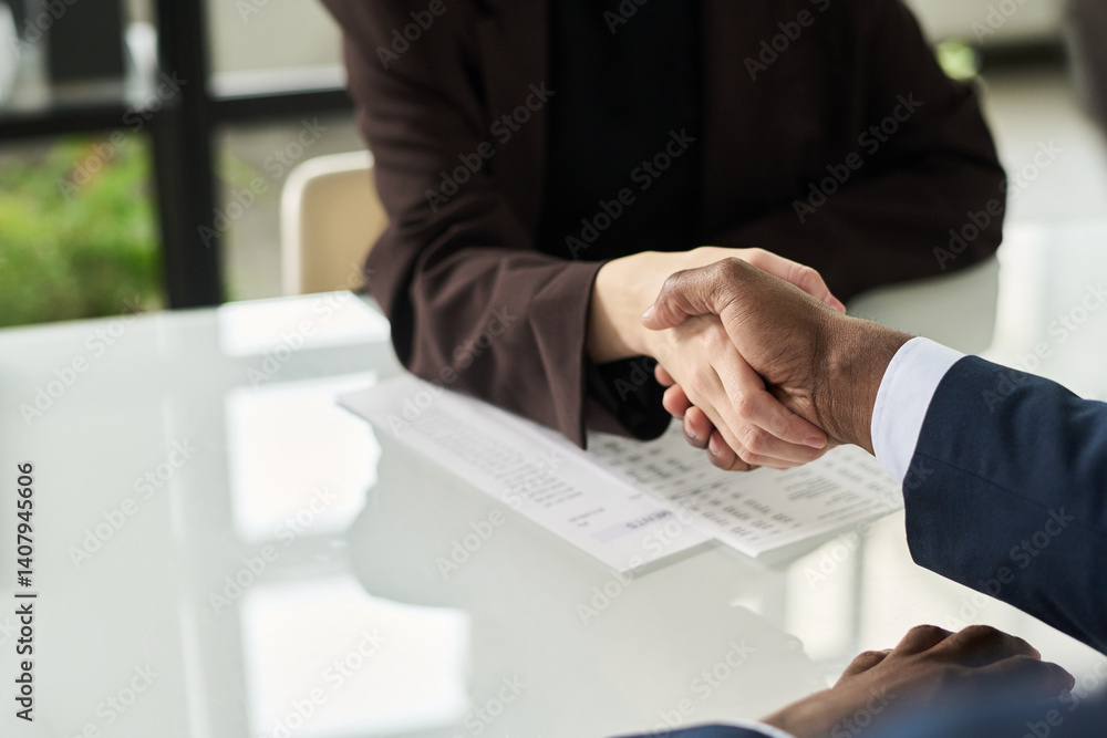 Poster close-up of colleagues shaking hands while sitting at table at meeting