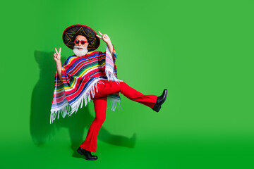 Vibrant man in colorful Mexican attire with a sombrero and poncho posing energetically against a...