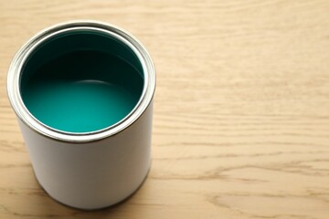 Can of turquoise paint on wooden background, closeup. Space for text