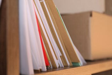 Different paper envelopes and parcel on shelf in post office, closeup