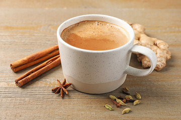 Aromatic Masala tea in cup and spices on wooden table, closeup