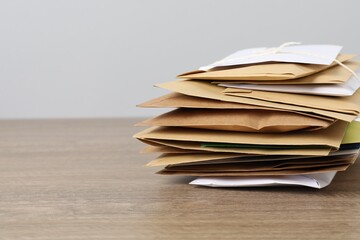 Post office. Stack of different paper envelopes on wooden table, closeup. Space for text