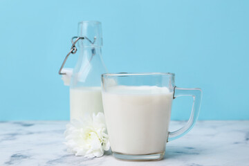Fresh milk and flower on white marble table against light blue background