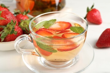 Aromatic fruit tea with strawberries and mint on white table, closeup