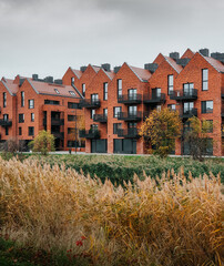 New houses in Gdansk. Modern residential district with lots of brick houses by river canal with dry aquatic plants.