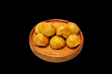 Nastar cookies with topping Egg yolk spread, served on wooden plate for Idul Fitri, Moselm Feast day. Traditional Cake in Indonesia Nastar Cake. Isolated on black background