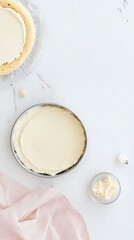 Top view of simple cake with white cream in baking tray and small bowl nearby