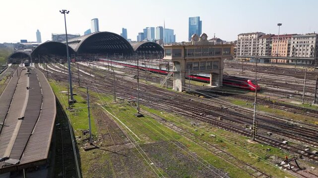 Europe,Italy, Milan 04,27,2025 drone view of Centrale train station railway with skyline in downtown - travel with Frecciarossa and Italo high speed trains to Bologna, Florence, Rome and Naples 