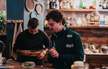 Two individuals are seen preparing food at a warmly lit and tidy kitchen. The setting captures a moment of culinary creativity and companionship, emphasizing the cozy ambience of the space.