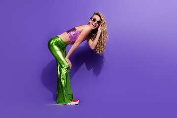Young woman in vibrant retro fashion posing playfully against a vivid purple background