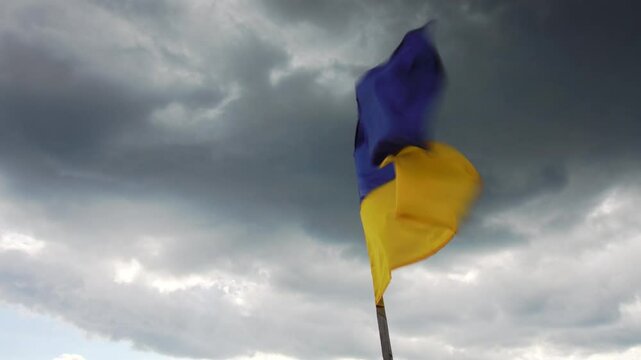 Ukrainian flag hardly flutters in the wind under the dark stormy sky
