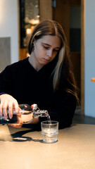 Young teenage girl drinks water from a transparent glass