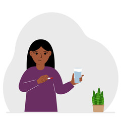 A little girl in one hand holds medicine or a pill in another glass of water. The concept of taking medicine to treat diseases, taking vitamins or food supplements with water.