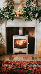 A fireplace with a white stove in front of it. The room is decorated with greenery and a yellow...