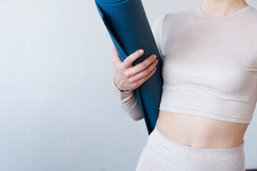 Beautiful girl getting ready for yoga indoors in daylight.