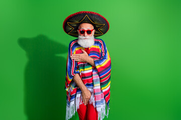 Charismatic man in traditional Mexican attire poses against vibrant green background portraying festive spirit and cultural charm