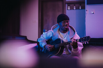 A talented musician performs on an acoustic guitar in a contemporary studio. The ambient lighting...