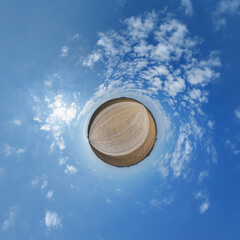 simple little tiny planet without buildings in blue sky with sun and beautiful clouds. Transformation of spherical panorama 360 degrees. Spherical abstract aerial view. Curvature of space.