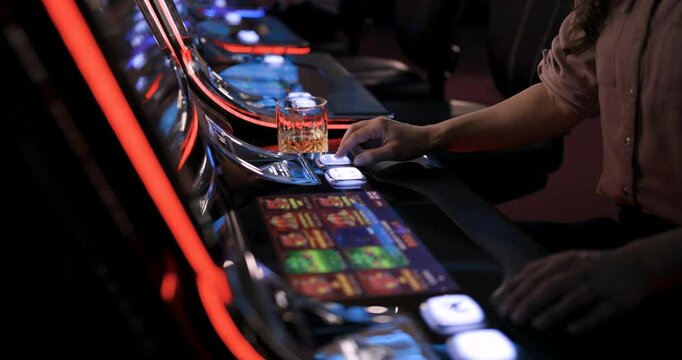 Woman Plays Slot Machine Game at Casino with Alcoholic Drink