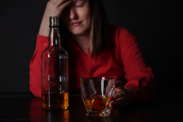 Alcohol addiction. Miserable woman with whiskey at table in dark, selective focus