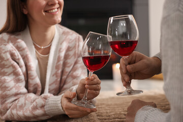 Couple with glasses of wine on floor at home, closeup