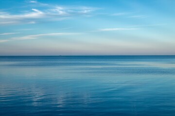 Fototapeta premium Vast turquoise waters stretch toward the horizon under a serene sky at twilight